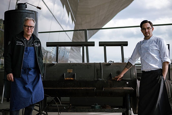 Bobby Bräuer, Zwei-Sterne-Koch aus dem Restaurant EssZimmer, zusammen mit dem Küchenchef der Bavarie, Dominik Kreuzig vor dem BBQ Smoker des Restaurants Bavarie by Käfer (©Foto: BMW Welt)